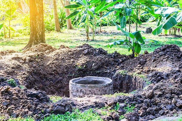 A hole with a pipe in it in the woods